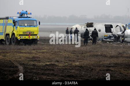 Einsatzkräfte stehen neben eines abgestürzten Flugzeugs auf dem Flughafen in Donezk, Ukraine, 14. Februar 2013. Mindestens fünf Menschen wurden nach einer An-24 Flugzeug Bruchlandung in der Nähe des Flughafens von der Ost-ukrainischen Stadt Donezk, tot wie Beamte sagten. Foto: Marius Becker/dpa Stockfoto