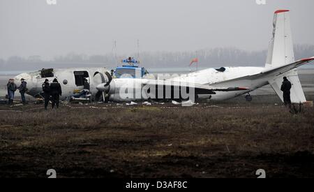 Einsatzkräfte stehen neben eines abgestürzten Flugzeugs auf dem Flughafen in Donezk, Ukraine, 14. Februar 2013. Mindestens fünf Menschen wurden nach einer An-24 Flugzeug Bruchlandung in der Nähe des Flughafens von der Ost-ukrainischen Stadt Donezk, tot wie Beamte sagten. Foto: Marius Becker/dpa Stockfoto