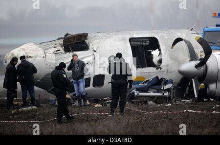 Einsatzkräfte stehen neben eines abgestürzten Flugzeugs auf dem Flughafen in Donezk, Ukraine, 14. Februar 2013. Mindestens fünf Menschen wurden nach einer An-24 Flugzeug Bruchlandung in der Nähe des Flughafens von der Ost-ukrainischen Stadt Donezk, tot wie Beamte sagten. Foto: Marius Becker/dpa Stockfoto