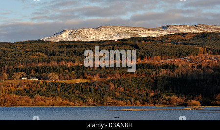 Entfernten weißen Häuschen in Waldlichtung, schneebedeckte Bergen über. Stockfoto