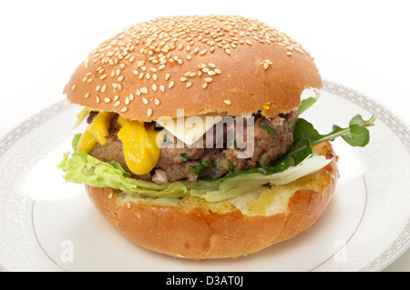 Eine hausgemachte Beefburger Patty in einem Sesam Brötchen, mit Salat, Rucola (Rakete), Senf und eine Scheibe Käse Stockfoto