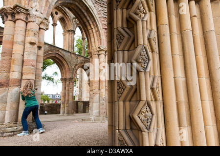 Teenager-Mädchen spielt und läuft unter den Überresten Jedburgh Abbey einen zerstörten Sie 12. Jahrhundert Augustiner Kloster in den Grenzen von Schottland Stockfoto