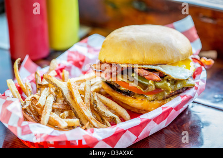 Korb mit Pommes Frites mit Cheeseburger und Ei Stockfoto