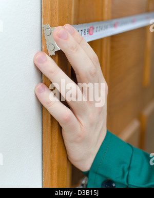 Junge Handwerker in Uniform mit Maßband Stockfoto