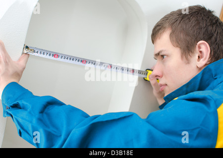 Junge Handwerker in Uniform mit Maßband Stockfoto