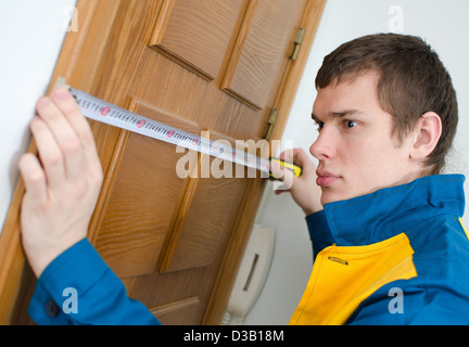 Junge Handwerker in Uniform mit Maßband Stockfoto