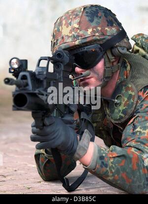 Ein Soldat, ausgestattet mit High-Tech-Waffe Prototypen zielt auf ein Ziel durch eine Laser-Augen auf seine Waffe in Hammelburg, Deutschland, 9. Dezember 2002 montiert. Der "Infanterist der Zukunft" trägt Kommunikation Antennen und ein Satelliten-Navigationssystem. Obwohl seine Weste stark gepanzert ist es ist Gewicht Stockfoto