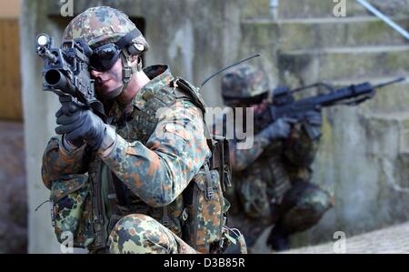 Ein Soldat, ausgestattet mit High-Tech-Waffe Prototyp zielt auf ein Ziel durch eine Laser-Augen auf seine Waffe in Hammelburg, Deutschland, 9. Dezember 2002 montiert. Der "Infanterist der Zukunft" trägt Kommunikation Antennen und ein Satelliten-Navigationssystem. Obwohl seine Weste stark gepanzert ist es ist Gewicht Stockfoto