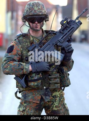 Ein Soldat, ausgestattet mit High-Tech-Waffe Prototyp zielt auf ein Ziel durch eine Laser-Augen auf seine Waffe in Hammelburg, Deutschland, 9. Dezember 2002 montiert. Der "Infanterist der Zukunft" trägt Kommunikation Antennen und ein Satelliten-Navigationssystem. Obwohl seine Weste stark gepanzert ist es ist Gewicht Stockfoto