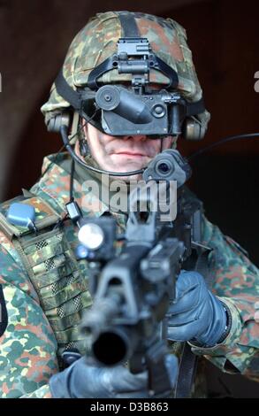 Ein Soldat, ausgestattet mit High-Tech-Waffe Prototyp zielt auf ein Ziel durch eine Laser-Augen auf seine Waffe in Hammelburg, Deutschland, 9. Dezember 2002 montiert. Der "Infanterist der Zukunft" trägt Kommunikation Antennen und ein Satelliten-Navigationssystem. Obwohl seine Weste stark gepanzert ist es ist Gewicht Stockfoto