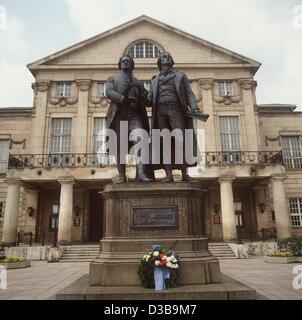 (Dpa-Dateien) - steht eine Skulptur des deutschen Dichter Johann Wolfgang von Goethe (L, 1749-1832) und Friedrich Schiller (1759-1805) vor dem Deutschen Nationaltheater Weimar, abgebildet im Dezember 1986. Klassisches Weimar mit seinen künstlerischen Gebäuden wurde ein UNESCO-Weltkulturerbe in erklärt. Stockfoto