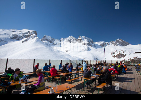 Skifahrer mit Mittagessen auf der Terrasse des Bergrestaurant über Zürs, Arlberg, Österreich. Stockfoto