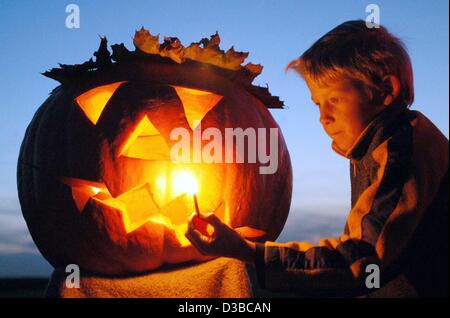 (Dpa) - kleine Patrick zündet eine Kerze im Inneren ein Halloween Kürbis in Kirchroth, Deutschland, 26. Oktober 2002. Die amerikanische Tradition der schreckliche Gesichter in Kürbisse Schnitzen bekommt in Deutschland immer beliebter. Der Ursprung der Tradition, geht aber zurück zweitausend Jahren bei den Kelten in Ir