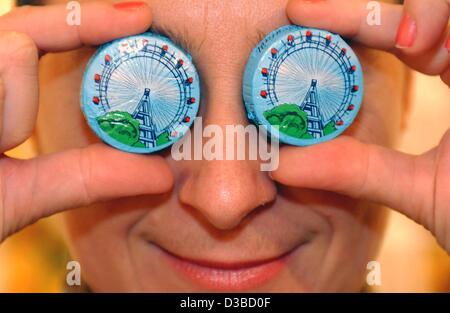 (Dpa) - eine junge Frau hält zwei süße Wiener Riesenräder vor ihren Augen, in Köln, 28. Januar 2003. Der Wiener Süßwaren Hersteller Walter Heindl macht diese Räder des Wiener Nougat. Stockfoto