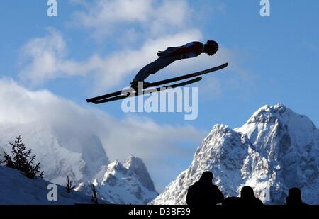 (Dpa) - ein Skispringer fliegt durch die Luft vor einen Panoramablick auf die schneebedeckte Zugspitze und Waxenstein Berge, bei einem Sprung aus dem Olympia Schanze (Olympia-Schanze) in Garmisch-Partenkirchen, Deutschland, 1. Januar 2003. Stockfoto