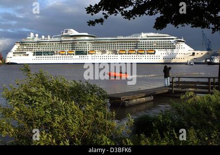 (Dpa) - ein Zuschauer steht am Ende eine kleine hölzerne Pier und Blicke über das Wasser, während ein Motorise Schlauchboot vorbei an den Ozean stürzt Kreuzfahrtschiff "Serenade of the Seas" und sie in Papenburg, Deutschland, 20. Juni 2003 Abdocken soll. Die Cruiser ist 293,2 Meter lang und hat eine eingetragene tonna Stockfoto