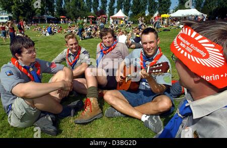 (Dpa) - eine Gruppe von Pfadfindern, Mitglieder der "Christlichen Pfadfinderschaft Deutschlands" (christliche Junge Pfadfinder-Verbindung in Deutschland) sitzen auf Rasen und hören Sie Musik während einer von ihnen spielt Gitarre während der Ökumenische Kirchentag in Berlin, 29. Mai 2003. Die ist das erste Mal, dass Cathol Stockfoto