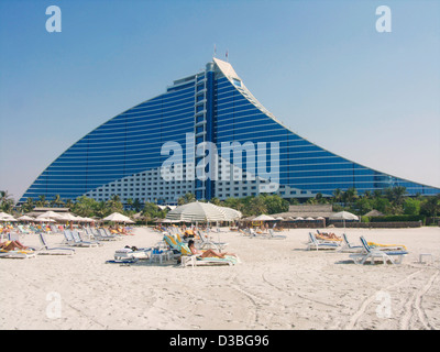 Der Strand vor dem Jumeirah Beach Hotel in Dubai UAE mit Liegestühlen und Sonnenschirmen mit Sonne Badegäste auf sie. Stockfoto