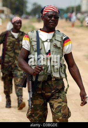 (Dpa) - zwei Hema Milizionär, die der "Military Police" der Union der kongolesischen Patrioten (UPC) angehören, patrouillieren die Straßen von Bunia, Kongo, 17. Juni 2003. Die Männer tragen die US-Flagge auf dem Kopf und ein T-shirt mit den deutschen Farben. Die Militärpolizei provoziert französische Truppen, die gesendet wurden Stockfoto