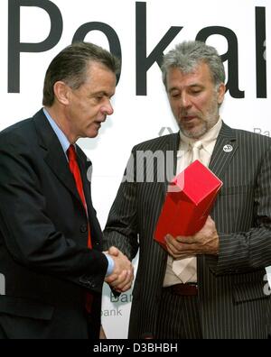 (Dpa) - Ottmar Hitzfeld, Fußball-Trainer des FC Bayern München, Bayern gratulieren, der Gewinn der deutschen Fußball-Bundesliga-Trophy in Berlin, 19. Mai 2003 präsentiert Eric Gerets (R), Fußball-Trainer des 1. FC Kaiserslautern, eine Flasche Rotwein. Ihre beiden Teams werden im nächsten DFB gegeneinander Stockfoto