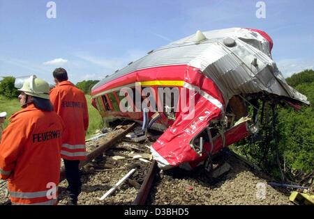 (Dpa) - ein abgestürztes Waggon steht über die Gleise, Feuerwehrleute sind daneben, Schrozberg, Deutschland, 11. Juni 2003. Zwei s-Bahnen kollidierte im ländlichen Südwesten Deutschlands, sechs Menschen getötet und verletzt wurden einige 25. Die Züge prallte frontal auf eine Single-Rail Strecke in der Nähe von Schrozberg Stockfoto