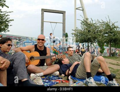 (Dpa) - entspannen Sie junge Menschen auf eine grüne im Mauerpark (Mauerpark) im Stadtteil Prenzlauer Berg in Berlin, Deutschland, 8. Mai 2003. Der Park ist ein Streifen von der ehemaligen Niemandsland entlang der Berliner Mauer, Teile davon sind mit Graffiti (im Hintergrund zu sehen) und erinnern an die Geschichte von der Stockfoto