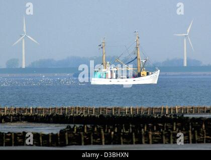 (Dpa) - Segel ein Trawler bequem entlang der Küste vorbei an zwei riesigen Windkraftanlagen auf dem Weg in den seichten Gewässern in der Nähe um Krabben in der Nähe von Husum, Deutschland, 30. April 2003 zu fangen. Stockfoto