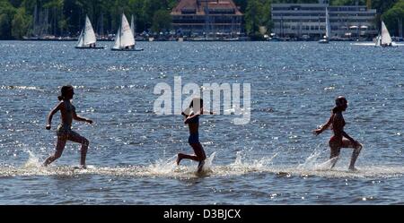 (Dpa) - drei junge Mädchen nehmen die Chancen und laufen Spritzwasser durch See am See Wannsee in Berlin, 5. Mai 2003. Stockfoto