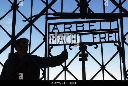 (Dpa-Dateien) - ein Mann schließt ein Eisentor mit der Aufschrift "Arbeit Macht Frei" (Arbeit macht frei), am Haupteingang, das ehemalige Konzentrationslager in Dachau, Deutschland, 22. März 2003. Dachau war das erste nationalsozialistische Konzentrationslager, gegründet am 22. März 1933, nur wenige Wochen nach Hitlers h Stockfoto