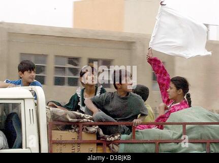 (Dpa) - ein irakisches Mädchen auflegt eine weiße Fahne beim Sitzen auf ihr Hab und gut in einem LKW in Bagdad, 13. April 2003. Stockfoto