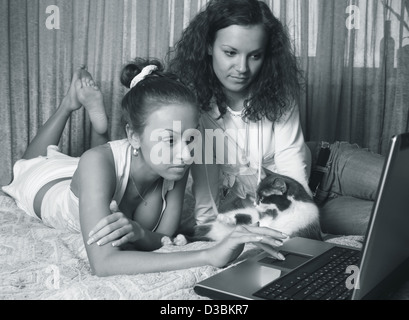 Zwei junge Mädchen eines Hauses mit Laptop und Katze Stockfoto