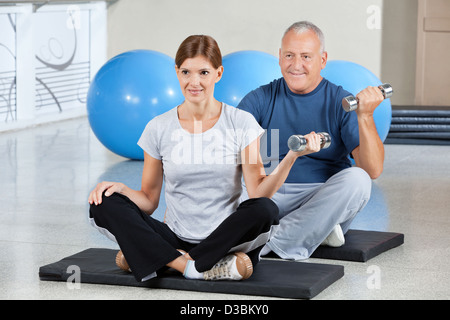 Mann und Frau auf Turnmatten mit Hanteln im Fitness-center Stockfoto