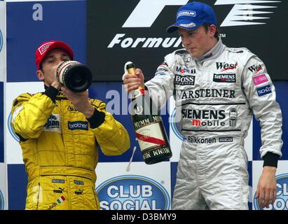 (Dpa) - finnische Formel 1 Pilot und Sieger Kimi Raeikkoenen (R) von McLaren-Mercedes und zweite Giancarlo Fisichella (Jordan-Team) Italien Drink Flaschen Champagner nach dem Gewinn des Grand Prix von Brasilien auf der Rennstrecke von Interlagos in Sao Paulo, Brasilien, 6. April 2003 gelegt. Raeikkoenen war de Stockfoto