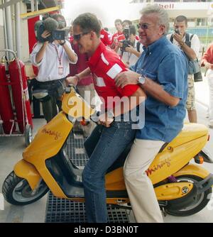 (Dpa) - kommt deutsche Formel-1-Weltmeister Michael Schumacher (vorne) mit seinem Manager Willi Weber auf einem Motorroller in Interlagos Formel 1 Rennstrecke in Sao Paulo, Brasilien, 3. April 2003. Der brasilianischen Formel Eins grand Prix ist das dritte Formel 1 Rennen nach Australien und Malaysia gr Stockfoto