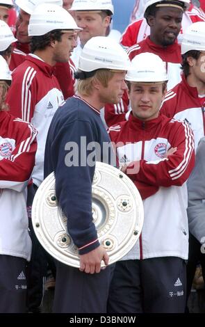 (Dpa) - Oliver Kahn (C), Teamkapitän und Torhüter des FC Bayern München, trägt die Bundesliga Trophy, während die Bayern München Spieler Schutzhelme in der neuen, aber noch unfertigen Allianz Arena in München, 20. Mai 2003 tragen. Die Allianz-Stadion wird voraussichtlich im Jahr 2005 fertig gestellt sein. Dann wird es bec Stockfoto