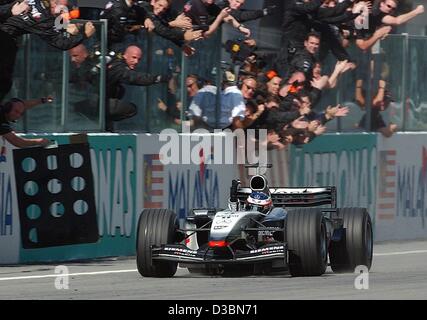 (Dpa) - finnischer Formel-1-Rennfahrer Kimi Raeikkoenen (McLaren-Mercedes) Gesten seines Sieges und fährt mit seinem Formel 1 Auto vorbei an eine Menschenmenge, die auf der Formel 1 Rennstrecke gewann er Formel 1 grand Prix in Sepang in der Nähe von Kuala Lumpur, Malaysia, 23. März 2003 jubeln. Es ist das erste Mal in seinem ca Stockfoto