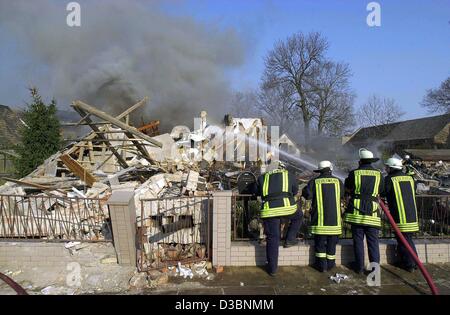 (Dpa) - Feuerwehrmänner Wasser eine schwelende Feuer in einem Einfamilienhaus nach einem mutmaßlichen Gasexplosion in Niederroeblingen, Deutschland, 14. April 2003. Ein Mann, der im Haus wohnte, wurde als vermisst gemeldet, wurden Details des Vorfalls nicht gegeben. Stockfoto