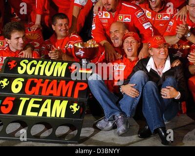 (Dpa) - feiert deutschen Formel-1-Fahrer Michael Schumacher Ferrari (vorne) mit seiner Frau Corinna (R) und das Ferrari-Team, nachdem er den WM-Titel nach der japanischen Formel Eins Grand Prix in Suzuka, 12. Oktober 2003. Schumacher platziert 8., gewann eine Rekord sechsten Welt Stockfoto