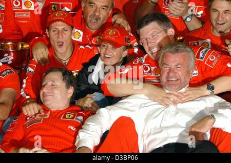 (Dpa) - deutscher Formel-1-Fahrer Michael Schumacher Ferrari (C links) feiert mit seiner Frau Corinna (C), Ross Brawn (R), Jean Todt (L, unten) und Manager Willi Weber (R) Nachdem er den WM-Titel nach der japanischen Formel Eins Grand Prix in Suzuka, 12. Oktober 2003. Schum Stockfoto