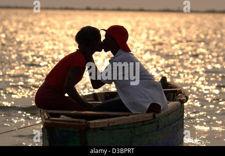 (Dpa-Dateien) Ein junges Paar teilt einen Kuss in der Abendsonne auf eine Fisherboat auf Benfica Strand, 30 Minuten außerhalb der Hauptstadt Stadt Luanda, Angola, 30. August 2003. Stockfoto