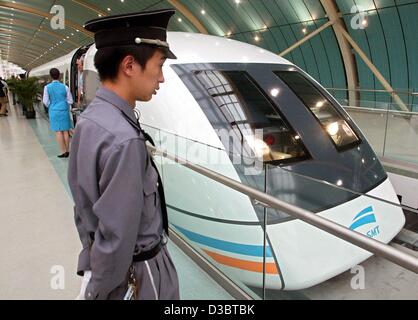 (Dpa) - ein Polizist steht Wache an die (Maglev) Magnetschwebebahn Transrapid in der Nähe des Bahnhofs in Shanghai, 15. September 2003. Die Maglev gebaut und entworfen von deutschen engineering Riesen Siemens und ThyssenKrupp, Links der weitläufige Metropole Shanghai zu seinen internationalen Flughafen Stockfoto