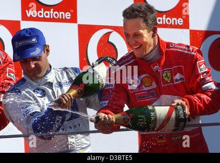 (Dpa) - der Gewinner des Grand Prix von Italien, deutsche Formel 1 pilot Michael Schumacher Ferrari (R) und Zweitplatzierten kolumbianischen Juan Pablo Montoya von BMW-Williams (L) Spritzen Champagner auf dem Podium auf der Rennstrecke in Monza, Italien, 14. September 2003 verfolgen. Schumacher führt die Gesamtwertung wi Stockfoto