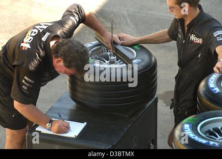 (Dpa) - Mechanik von McLaren-Mercedes Team akribisch nehme das Maß der Rennreifen, bei der Formel 1 Rennstrecke in Monza, Italien, 11. September 2003. Der neuen Michelin-Reifen scheinen mit den Motorsport-Regeln entsprechen. Die Formel eine Welt-Dachverband, FIA, erhielt McLaren und Williams die g Stockfoto