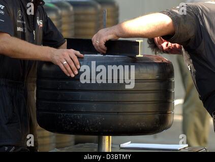 (Dpa) - Mechanik von McLaren-Mercedes Team akribisch nehme das Maß der Rennreifen, bei der Formel 1 Rennstrecke in Monza, Italien, 11. September 2003. Der neuen Michelin-Reifen scheinen mit den Motorsport-Regeln entsprechen. Die Formel eine Welt-Dachverband, FIA, erhielt McLaren und Williams die g Stockfoto