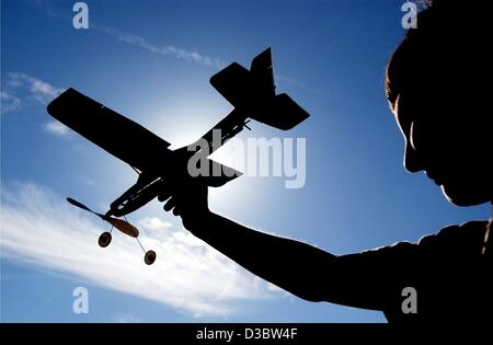 (Dpa) - die Silhouette eines jungen hält ein Modellflugzeug ist gegen die Sonne auf einer Wiese in Dietzenbach, Deutschland, 26. August 2003 gesehen. Stockfoto