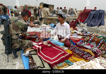 (Dpa) - ein deutscher Soldat sieht, in seiner Freizeit durch Stapel von Teppichen, Textilien und andere waren auf dem Stand von einem Straßenhändler in Kabul, Afghanistan, 3. August 2003. Mit mehr als 1.500 Soldaten in International Sicherheit Assistance Force (ISAF) beteiligt sich Deutschland weiterhin die Stockfoto