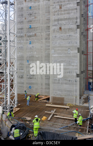 Arbeiter auf einer Website Construcion arbeiten unter der Betonkern ein neues Gebäude in der City of London errichtet. Die zentrale Liftschacht eines neuen Bürogebäudes erhebt sich das Team der Arbeitnehmer Köpfe - die Zahl der zukünftigen Stockwerke in diesem Gebäude, das auf London Wall, in die Hauptstadt Bankenviertel, bekannt als die Square Mile, nach seinen kreisenden römische und mittelalterliche Mauer gebaut wird. Stockfoto