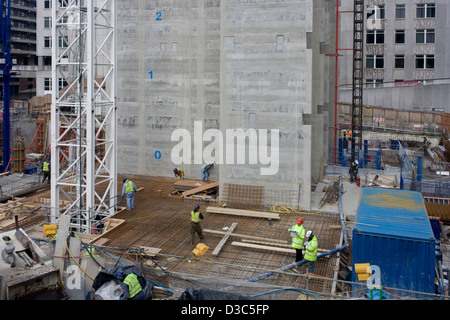 Arbeiter auf einer Website Construcion arbeiten unter der Betonkern ein neues Gebäude in der City of London errichtet. Die zentrale Liftschacht eines neuen Bürogebäudes erhebt sich das Team der Arbeitnehmer Köpfe - die Zahl der zukünftigen Stockwerke in diesem Gebäude, das auf London Wall, in die Hauptstadt Bankenviertel, bekannt als die Square Mile, nach seinen kreisenden römische und mittelalterliche Mauer gebaut wird. Stockfoto