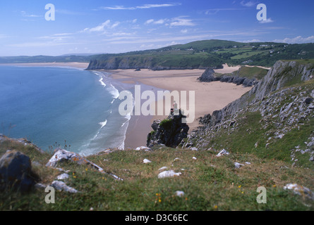 Einsame männliche Walker sitzen auf den Felsen mit Blick auf Three Cliffs Bay Gower Halbinsel South Wales UK Stockfoto