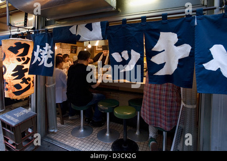 Gönner hinter Vorhang von Noren genießen Sie gutes Essen und Freundschaft am Zähler lokal in Omoide Yokocho, Memory Lane, Shinjuku, Tokio Stockfoto